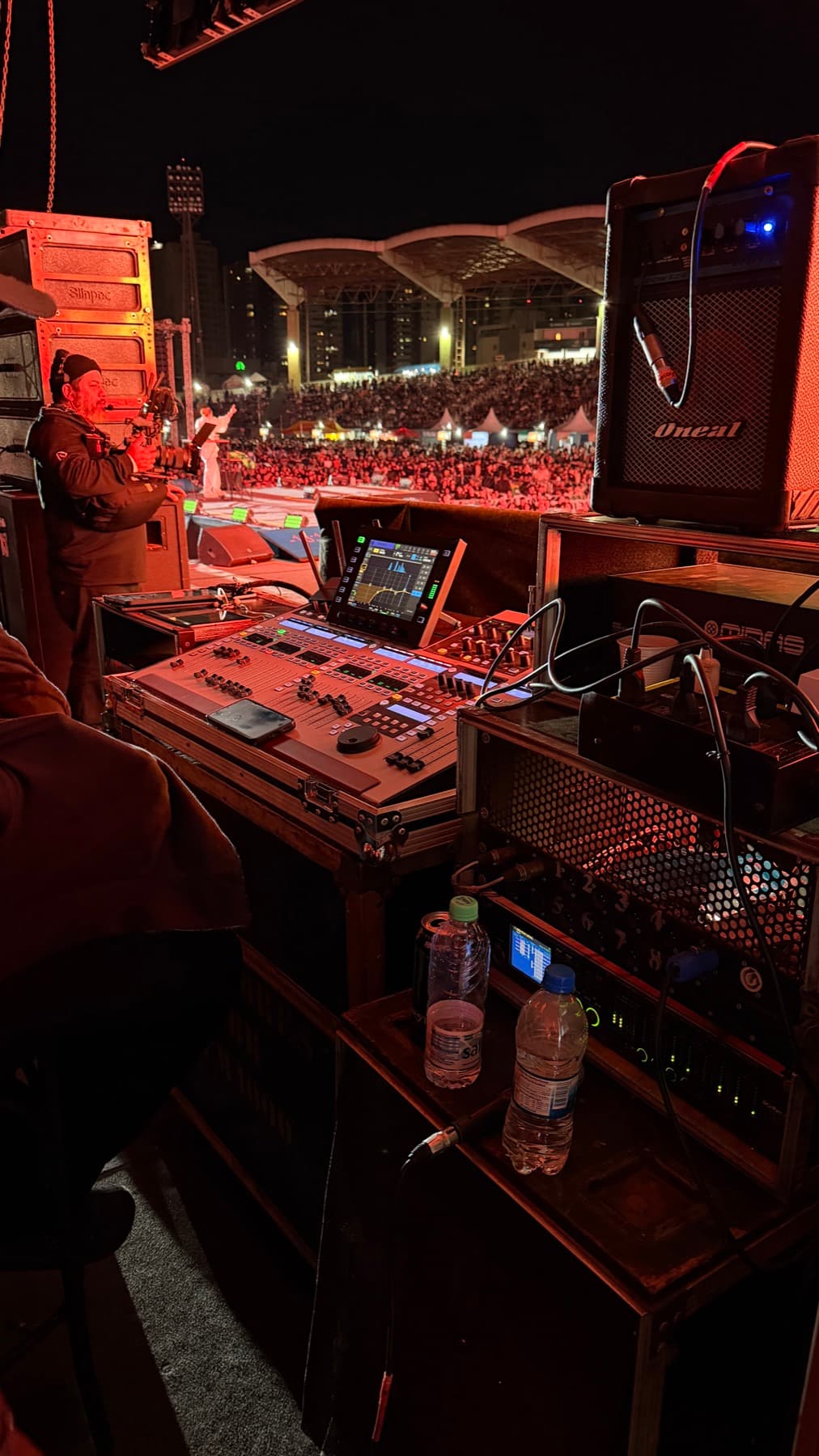 Monitor console backstage at Milagres Maringá 2026, the crowd bathed in red light